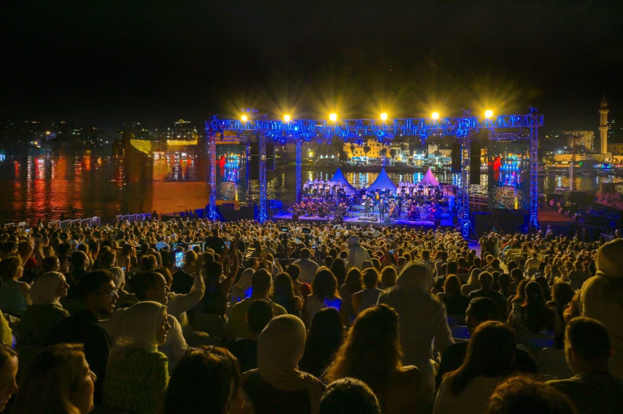 FrontRow live concert at night — packed crowd facing a floodlit seaside stage